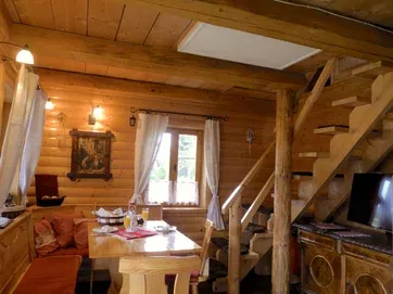Obývacia časť s dreveným stolom a schodmi do podkrovia